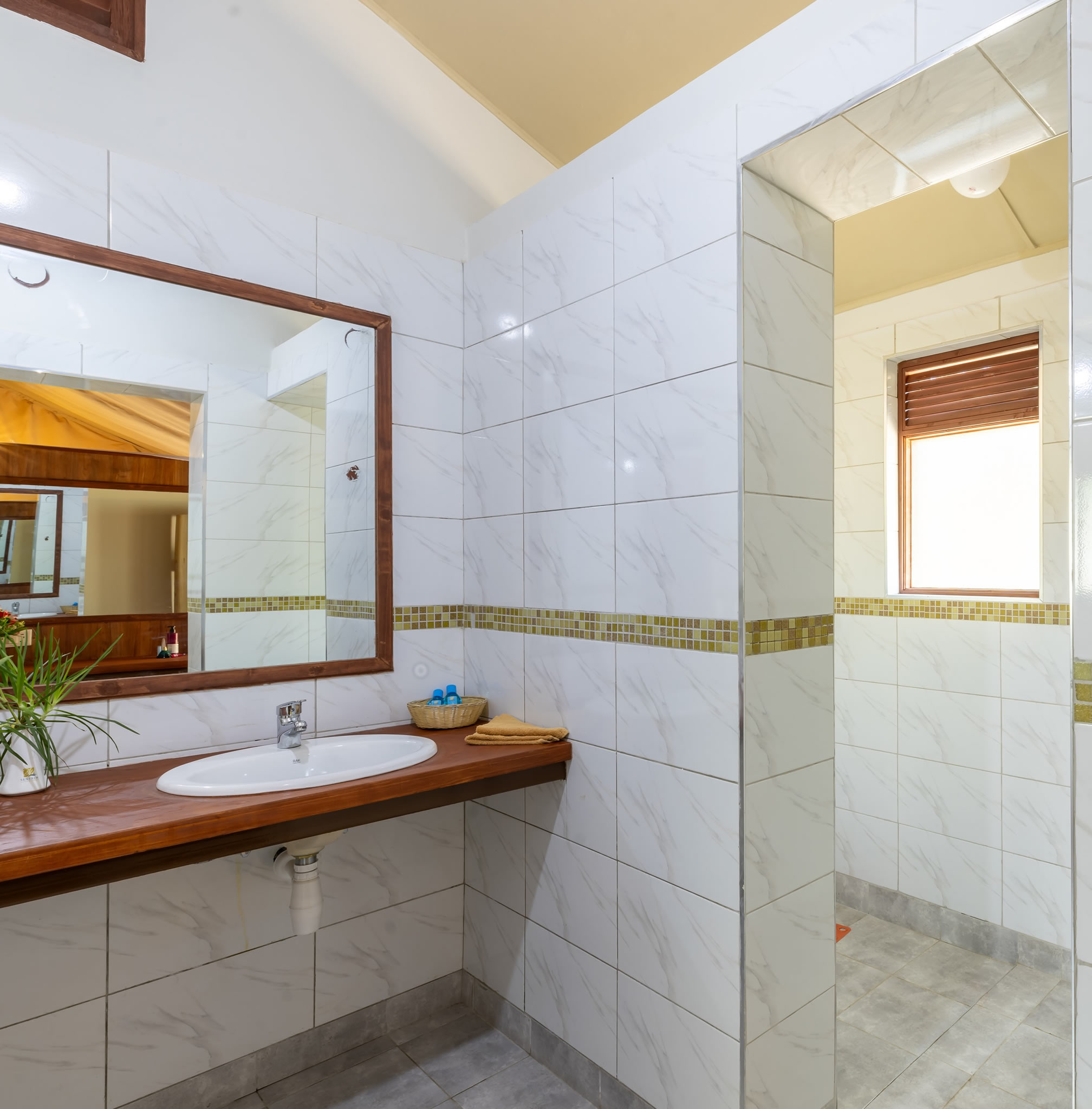 Modern en-suite safari bathroom with walk-in shower, vanity sink, and premium amenities at Sentrim Mara Camp in Maasai Mara, Kenya, offered by Cruzeiro Safaris Kenya.