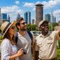 Happy tourists exploring Nairobi city with a professional Cruzeiro Safaris guide, featuring iconic landmarks including KICC, Nairobi skyline, Uhuru Park, and historic city monuments during a guided Nairobi City Tour.