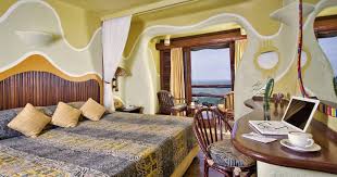 Double room at Mara Serena Safari Lodge with large windows overlooking the sweeping plains of Masai Mara.