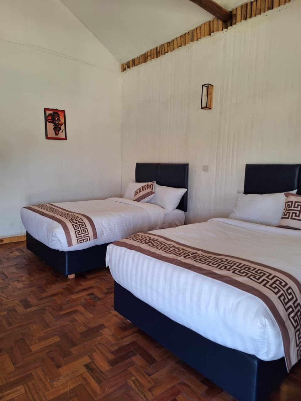 Comfortable twin room at Ambo Kili Cottages near Amboseli National Park, featuring two single beds and modern amenities for guests on safari with Cruzeiro Safaris Kenya.